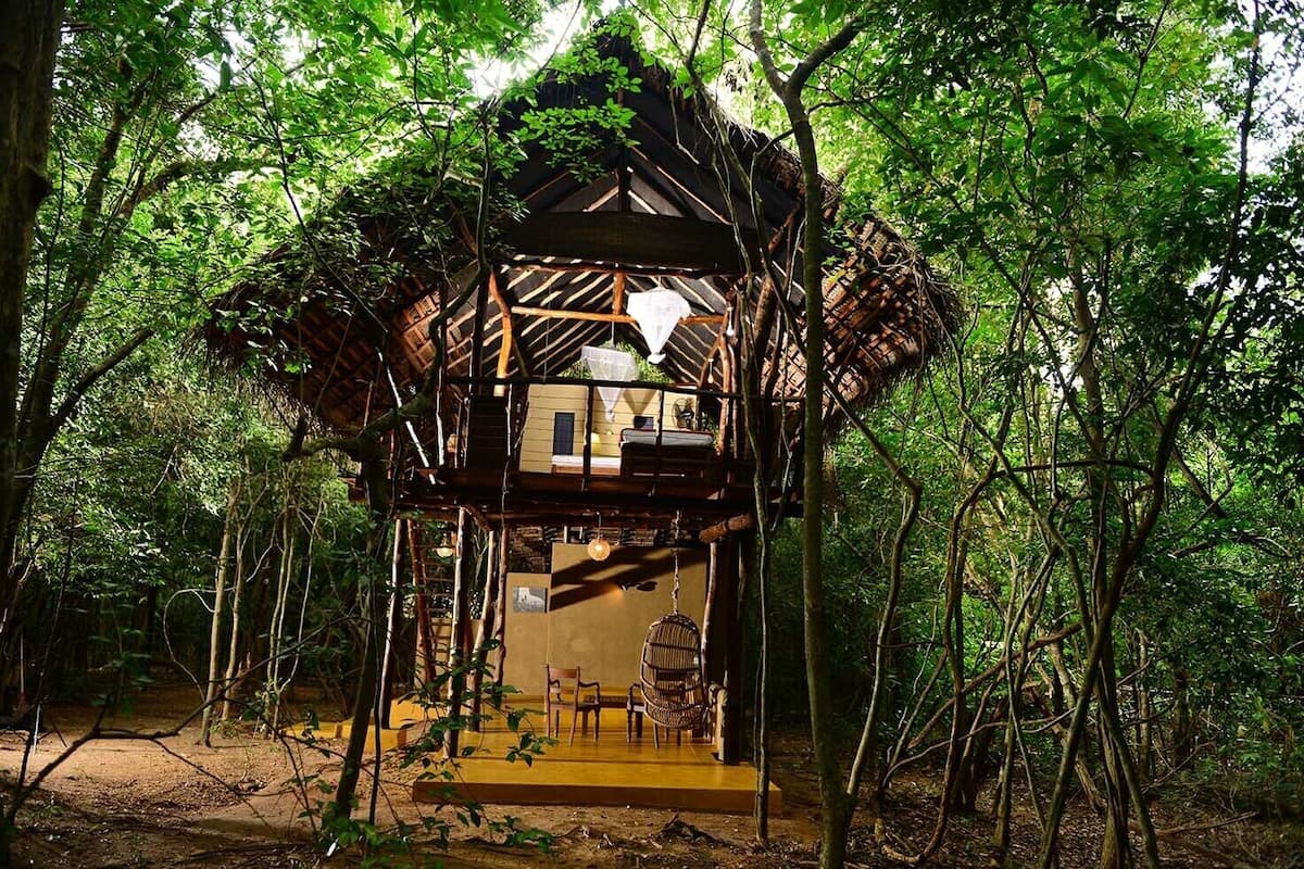 A treehouse with a wooden structure, a balcony, and a small seating area.