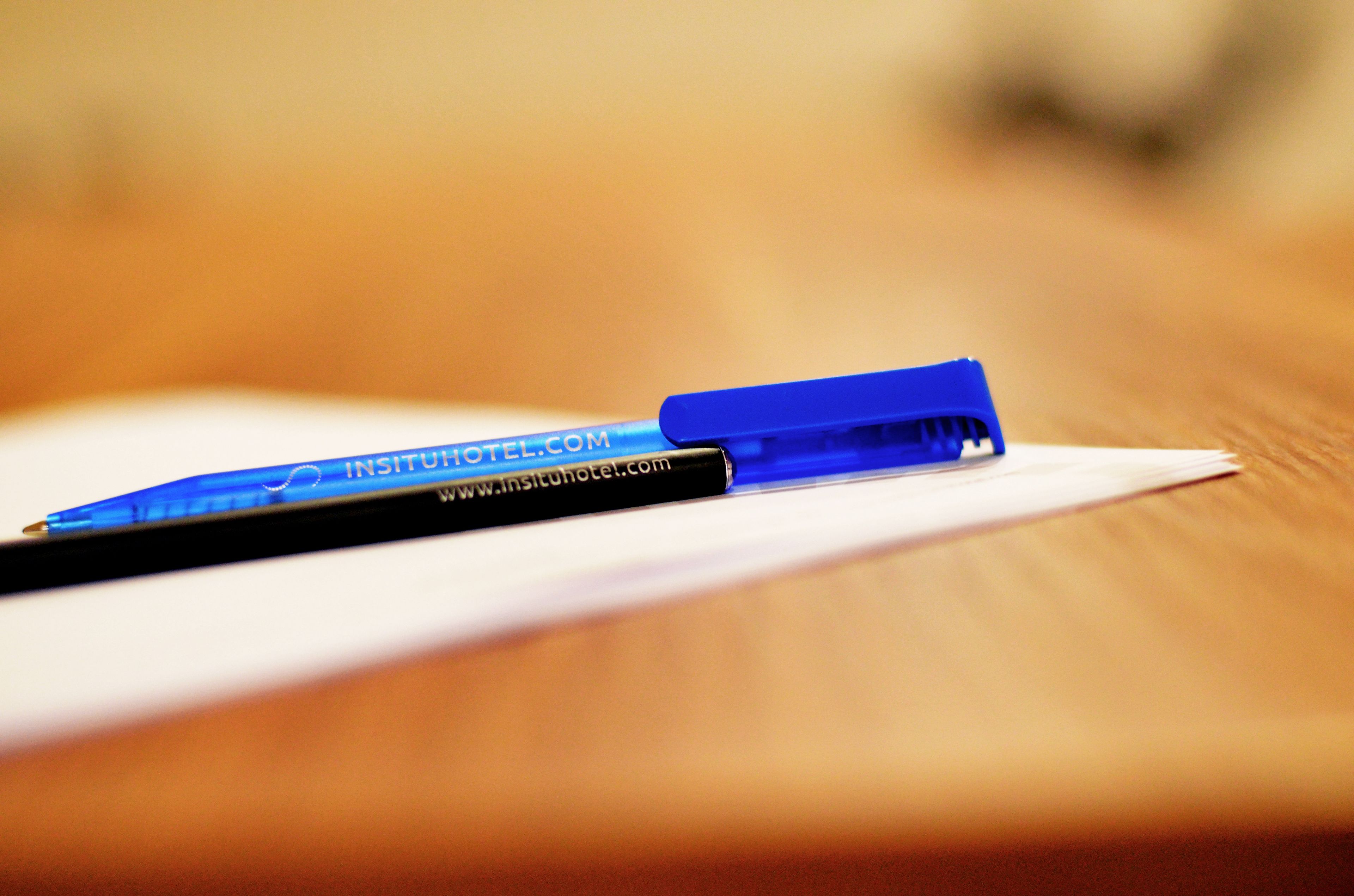 A blue pen on a white sheet of paper on a wooden surface.