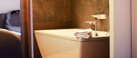 A modern bathroom with a freestanding bathtub, a towel on the edge, and a wall-mounted mirror.