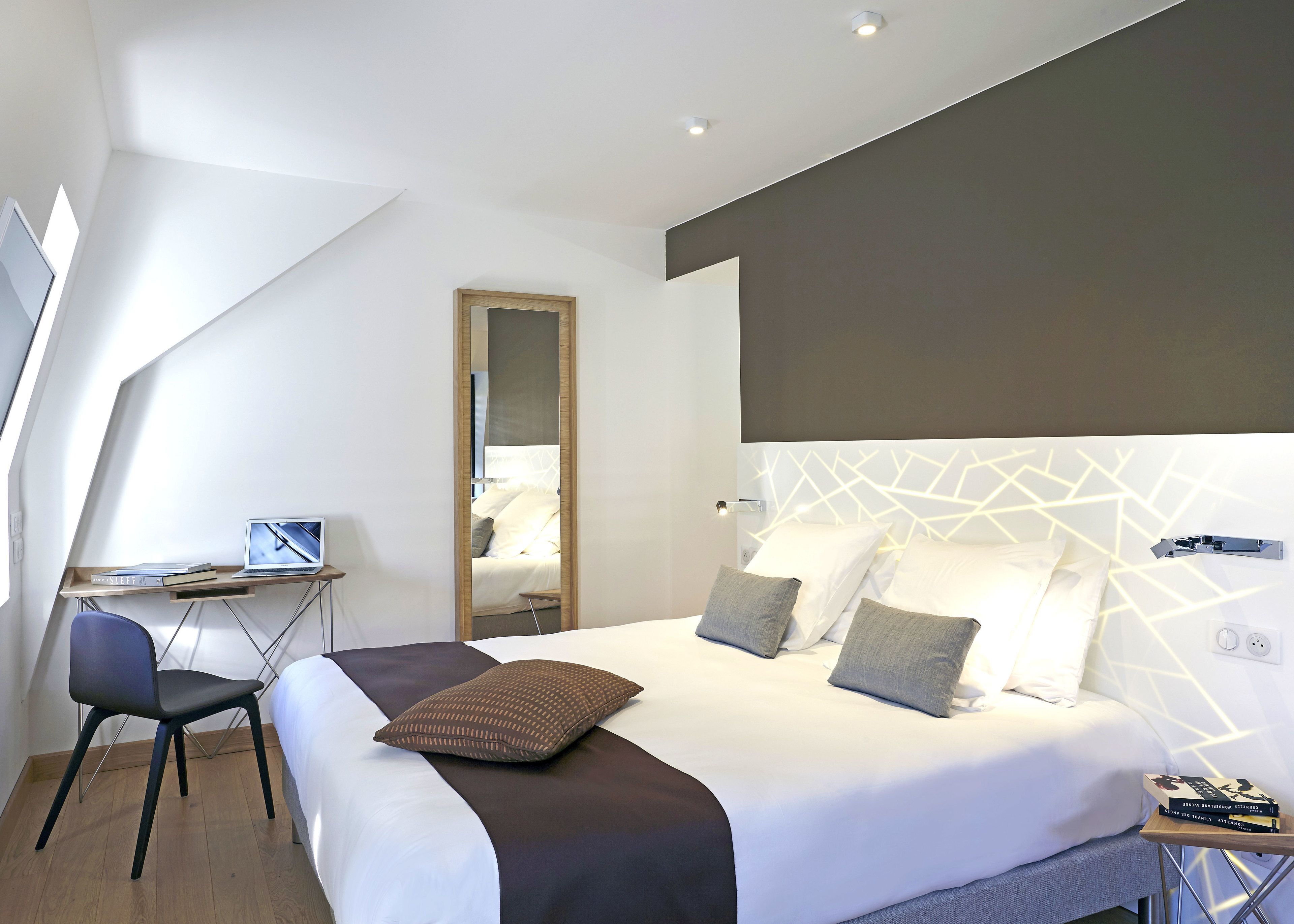 A modern hotel room with a bed, a desk, and a chair.