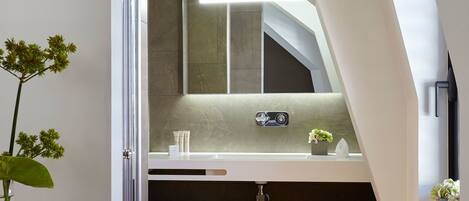 A modern bathroom with a skylight, a large mirror, and a wooden floor.