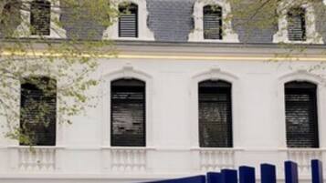 A white building with blue accents and a car parked in front.