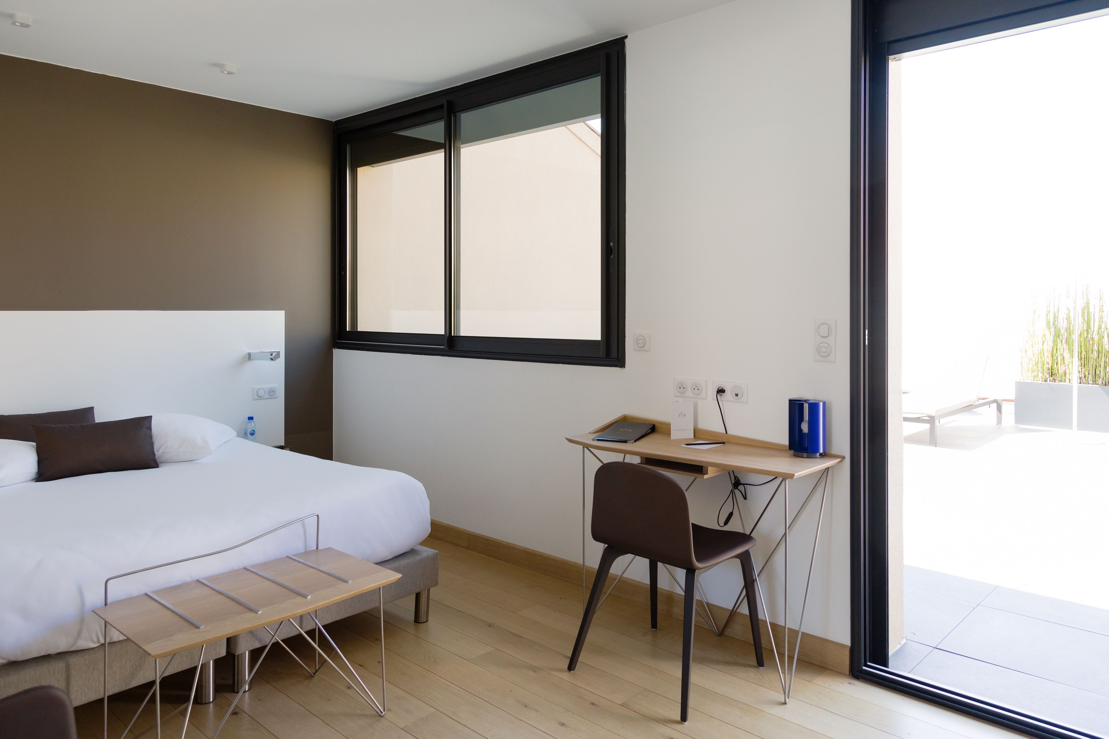 Un dormitorio moderno con cama, escritorio y silla, un ventanal y vistas al exterior.