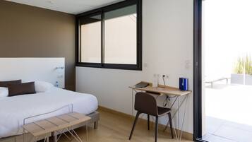 Un dormitorio moderno con cama, escritorio y silla, un ventanal y vistas al exterior.