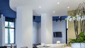 A modern reception area with a curved white reception desk, black chairs, and a large potted plant. - Hôtel In Situ (Béziers)