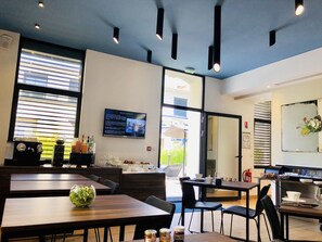 A modern dining area with tables, chairs, and a television displaying room service information.