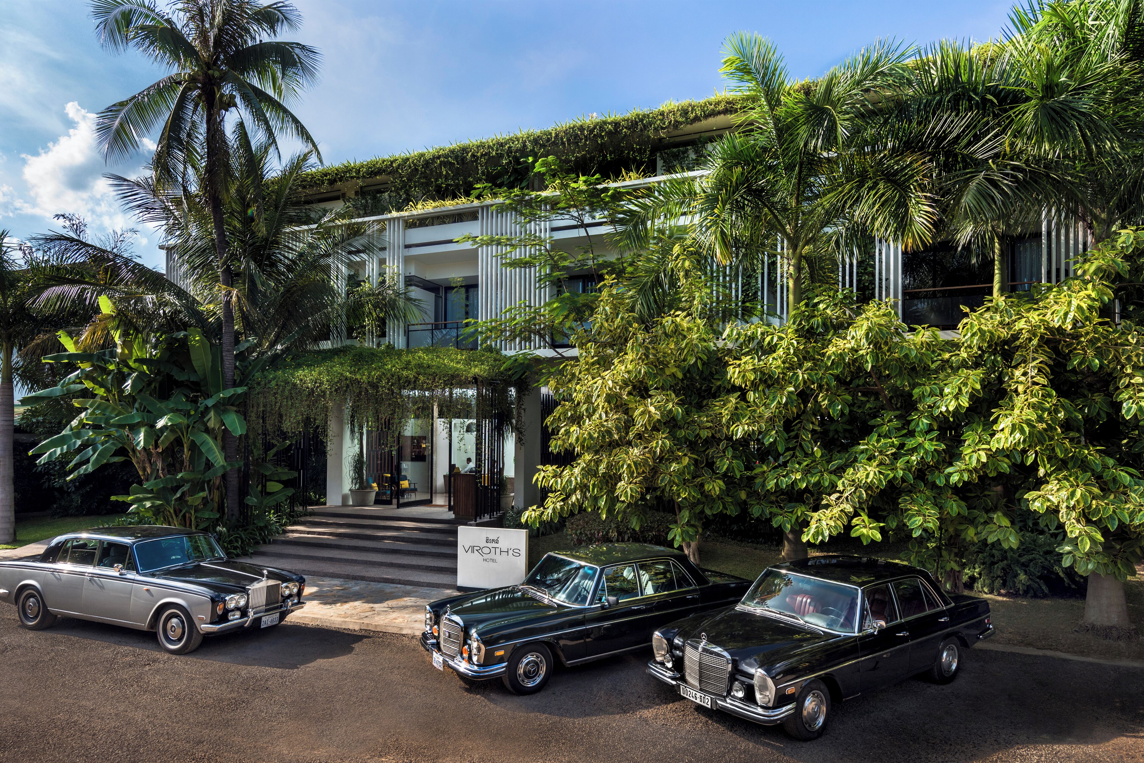 Un hôtel au design moderne, avec une structure à deux étages, une entrée couverte et une végétation luxuriante.
