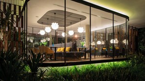 Un intérieur moderne doté d’une paroi incurvée en verre, d’un canapé et d’un coin repas avec des chaises et une table.