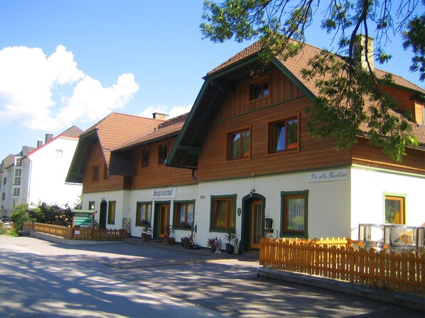 A traditional wooden building with a sloped roof, a sign reading "Spulauerhof," and a small porch area with potted plants.