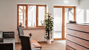 A modern room with a wooden desk, a chair, a potted plant, and a wooden dresser.