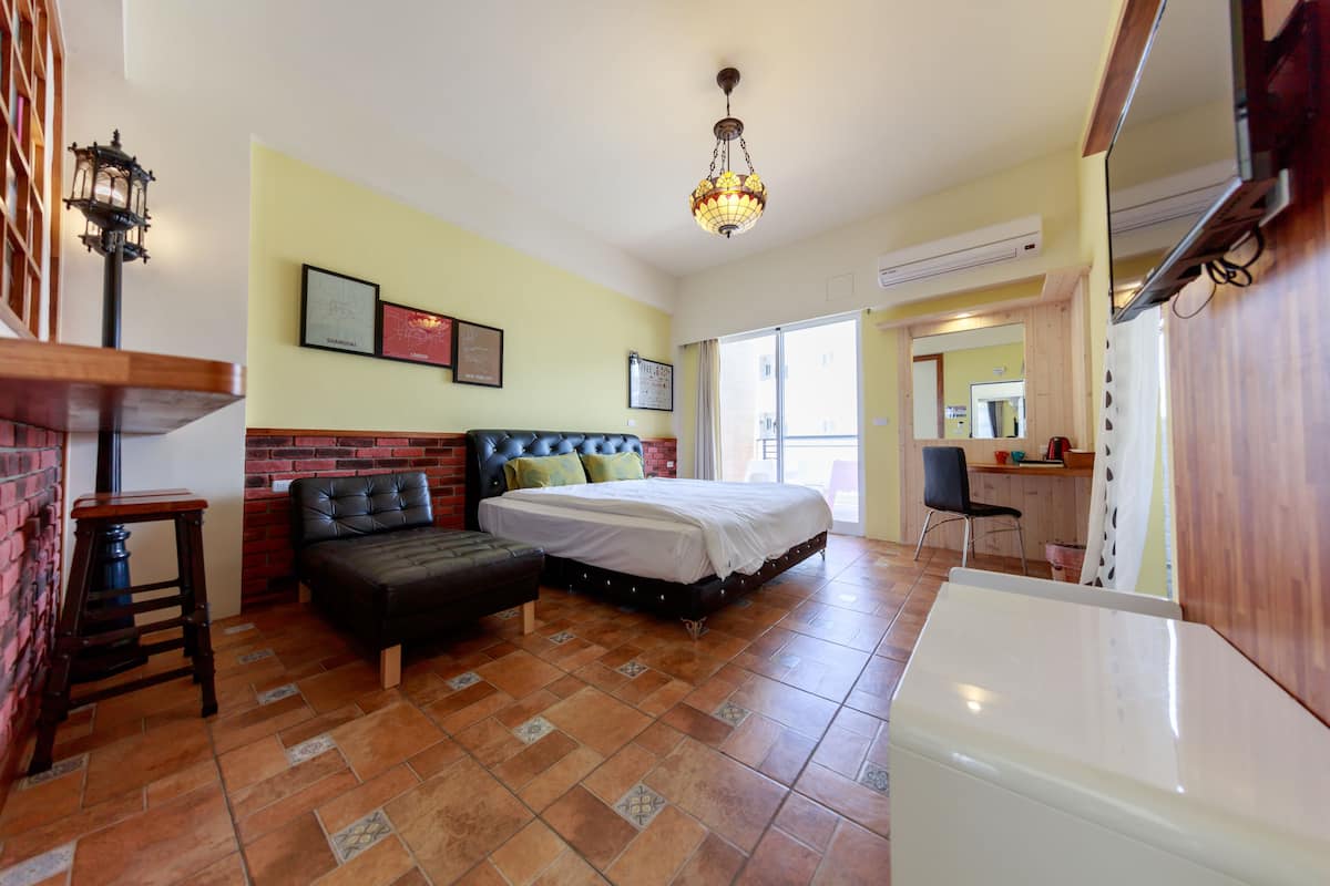 Una habitación con una cama, un sofá, una mesita y un televisor.