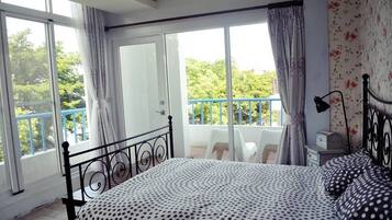 Un dormitorio con cama, una mesita de noche, una lámpara y vistas a un balcón con una silla.