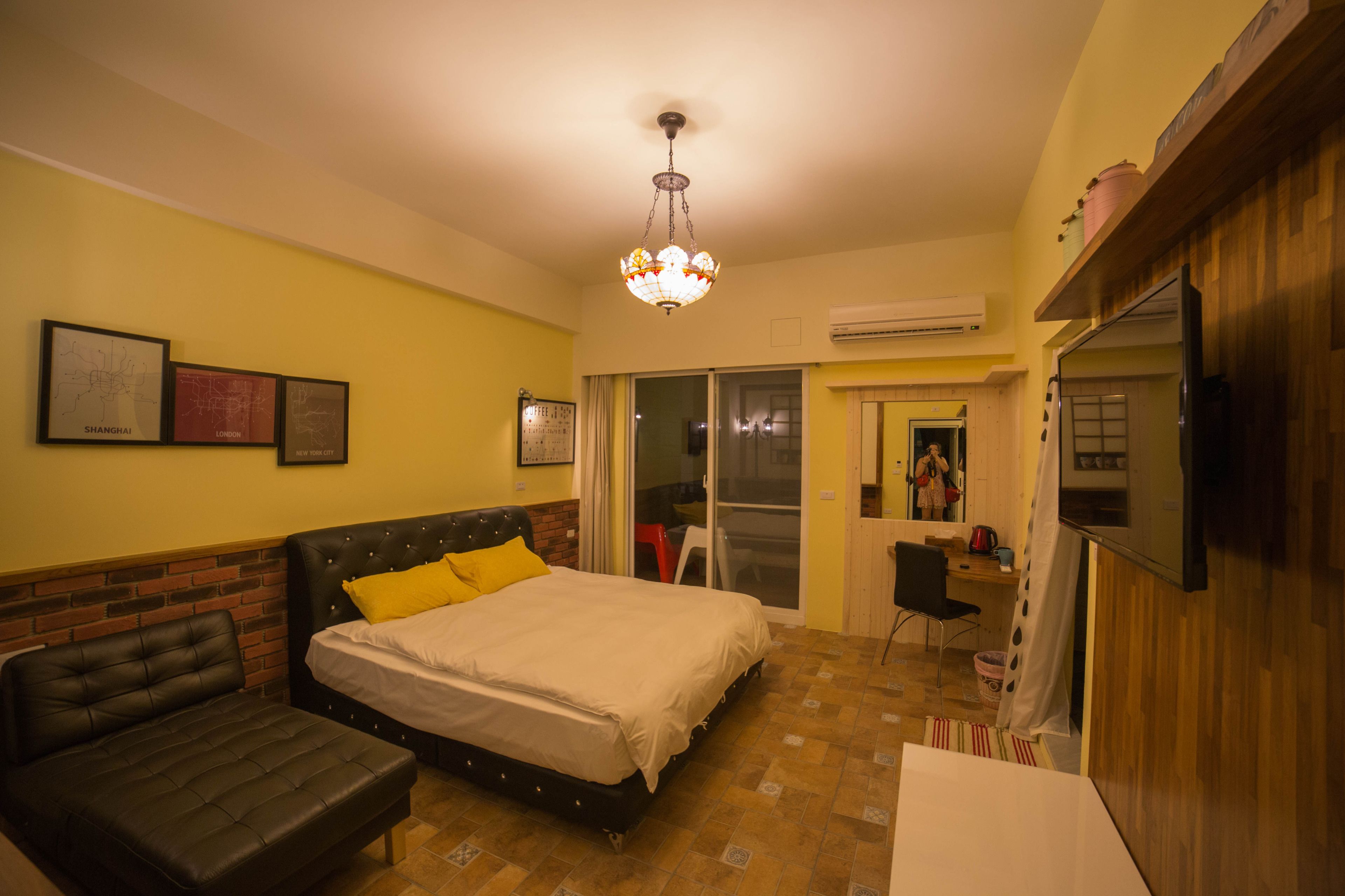 A bedroom with a bed, a sofa, a TV, and a chandelier.