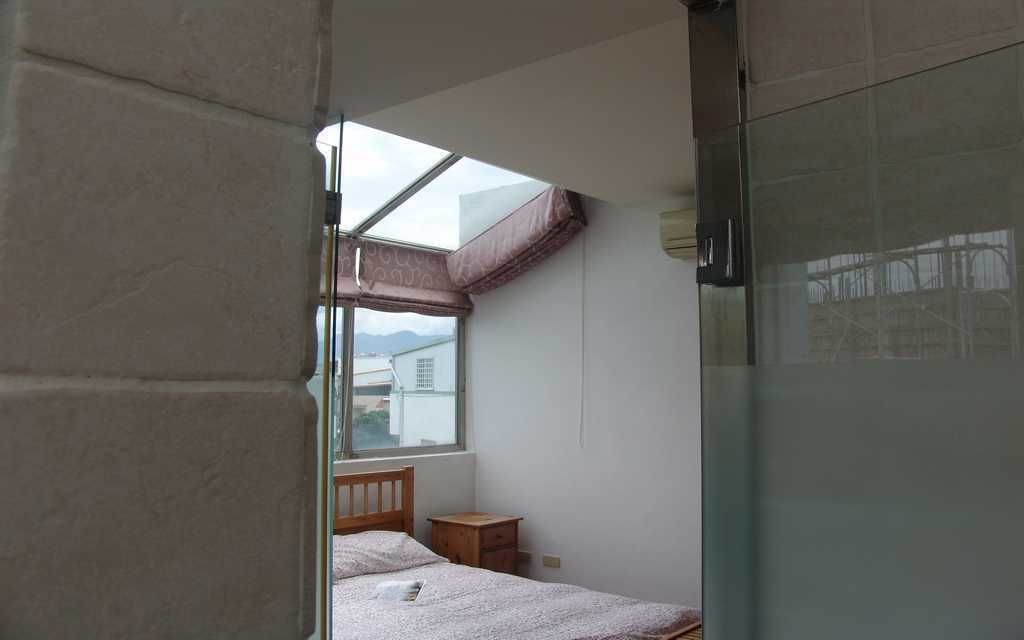 Une chambre avec une lucarne, un lit, une table de chevet et une cabine de douche en verre.
