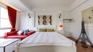 Un dormitorio moderno con una cama blanca, sofá rojo y una reproducción decorativa de la Torre Eiffel.
