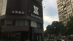 Un hôtel avec une enseigne bien visible indiquant « VIA HOTEL », une adresse clairement affichée et une enseigne « WOW » placée sous l’entrée.