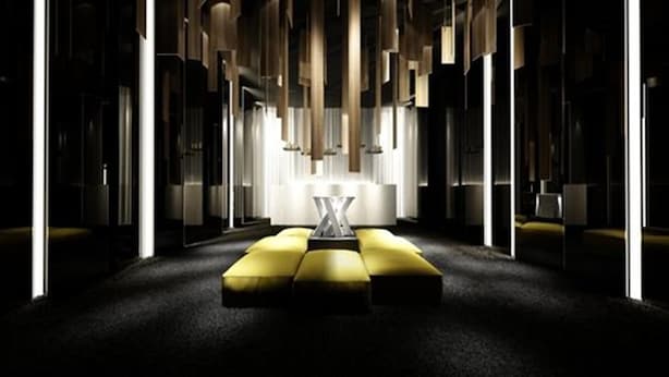 Un hall d’hôtel moderne doté d’un espace salon central, de grandes fenêtres et d’un design minimaliste.