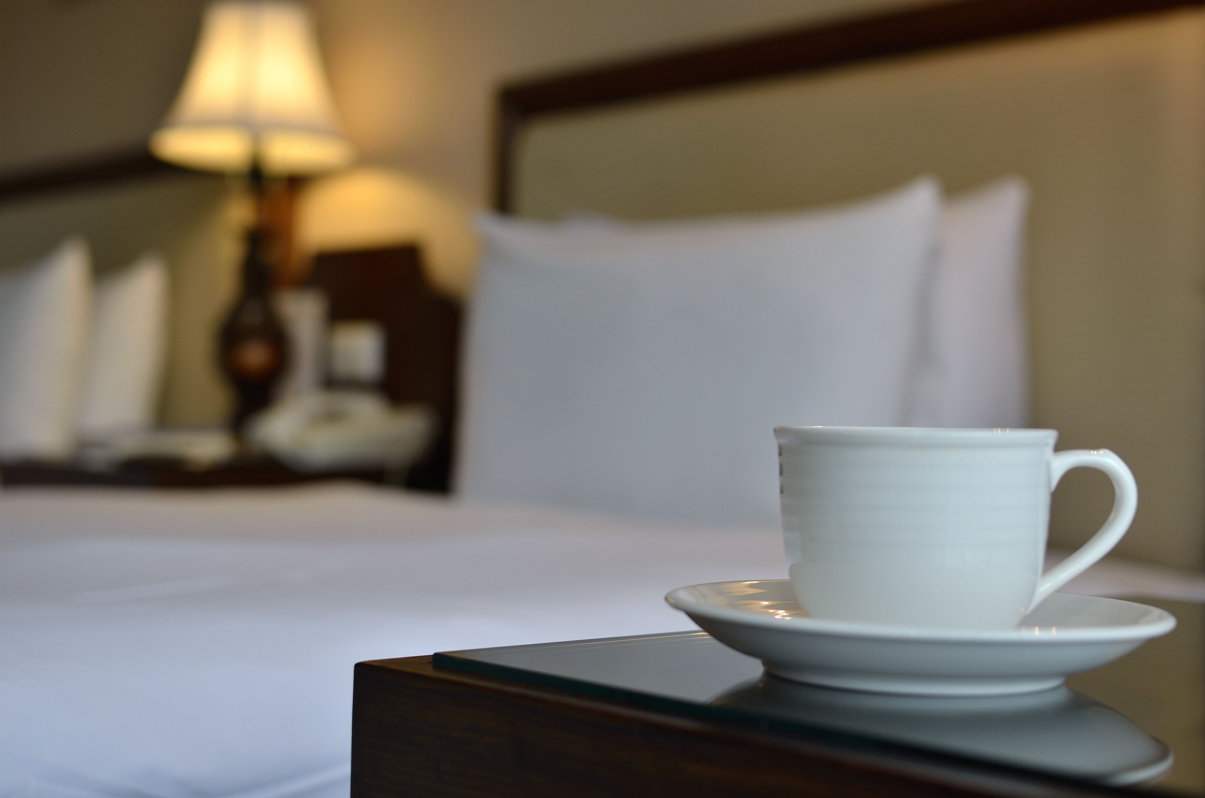 Une tasse blanche posée sur une soucoupe, sur une table dans une chambre d’hôtel.
