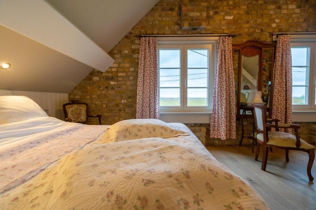 Ein Schlafzimmer mit einem großen Bett, einer hölzernen Kommode und einem Fenster mit Vorhängen.