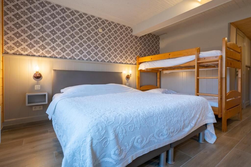 Une chambre avec un lit superposé, une table de chevet et un papier peint à motifs.