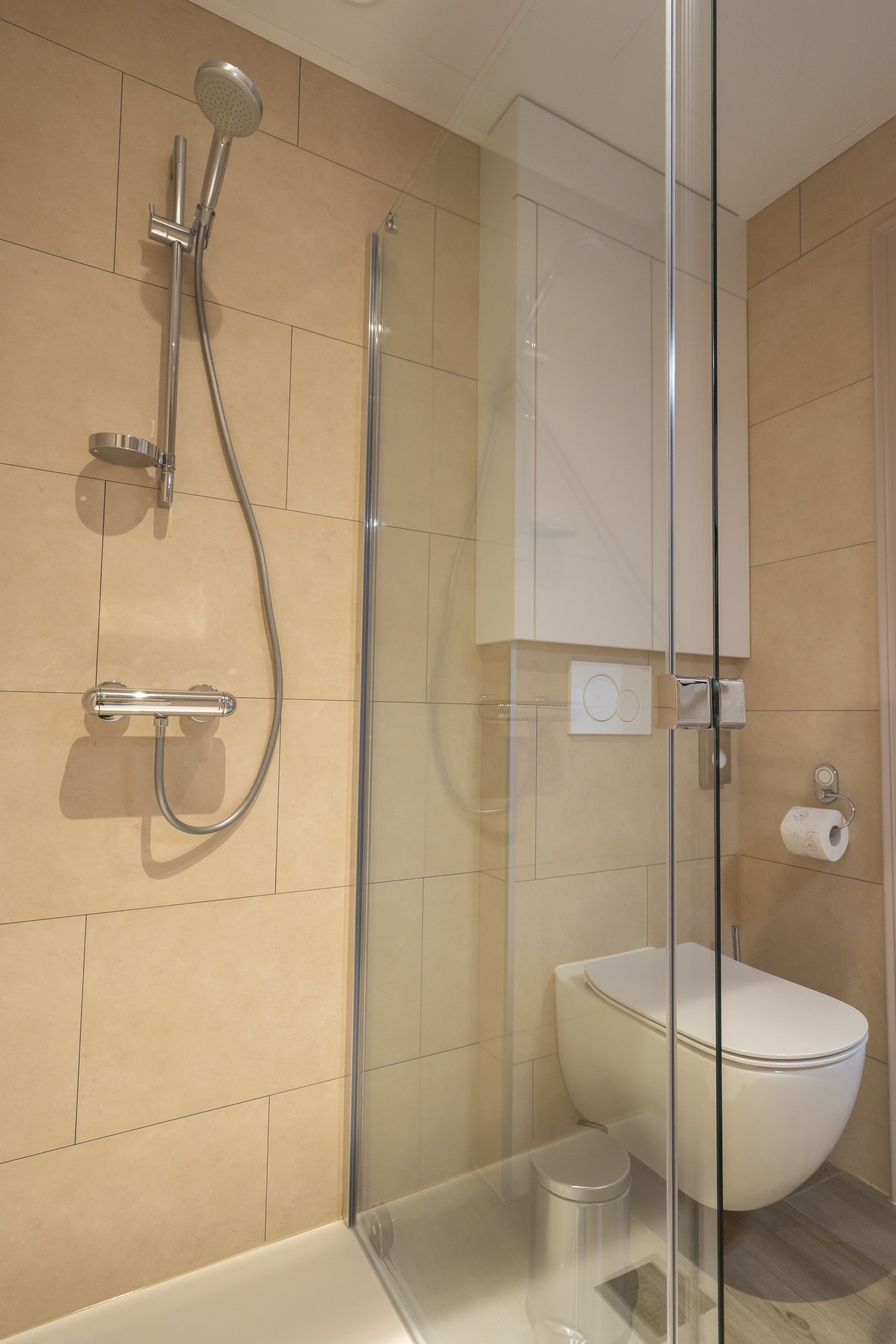 A modern bathroom with a glass-enclosed shower, a white toilet, and a glass shower door.