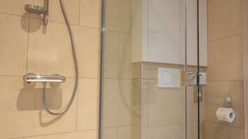 A modern bathroom with a glass-enclosed shower, a white toilet, and a glass shower door.