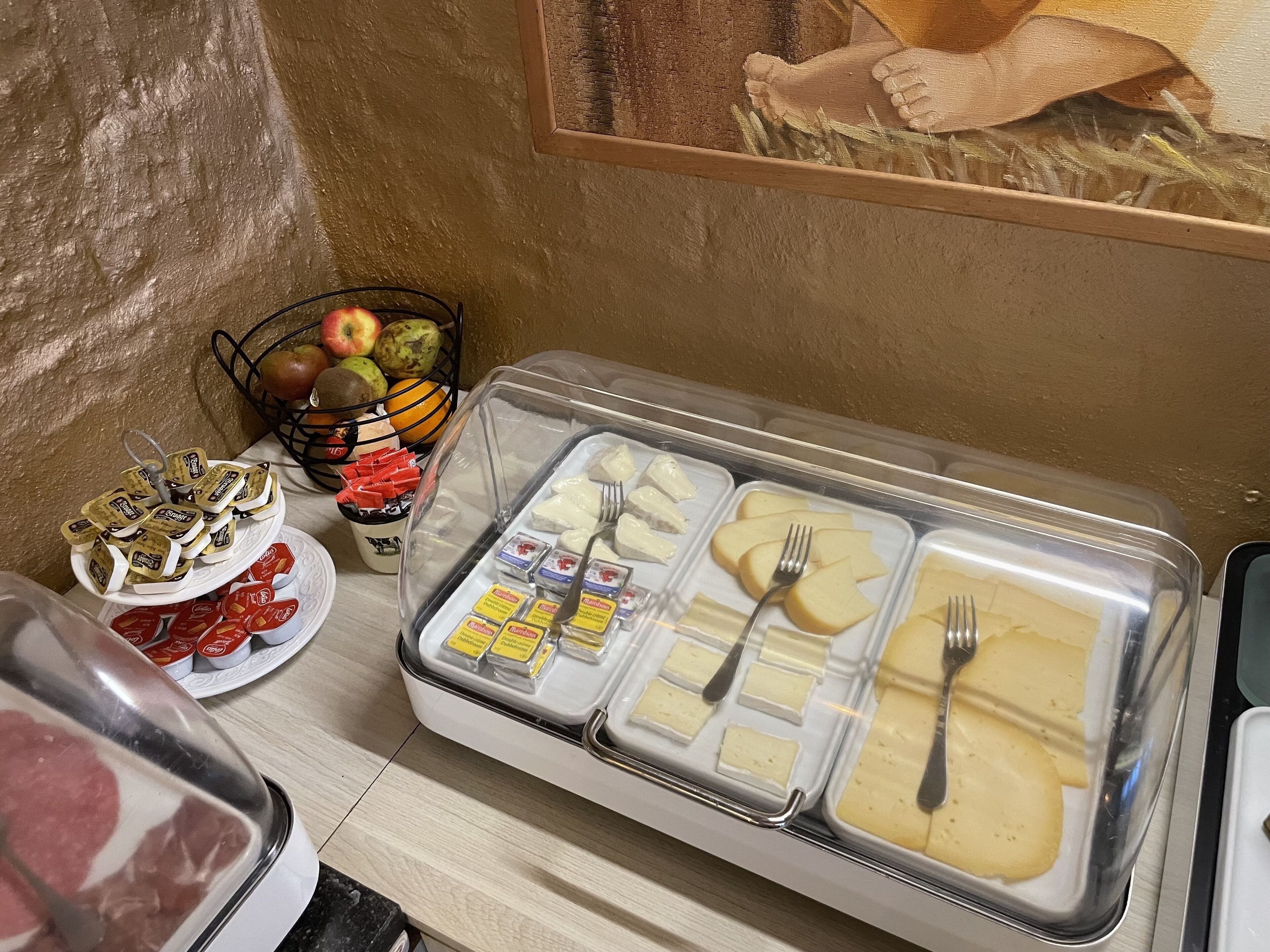 Buffet com diversos alimentos, incluindo queijo, frutas e acompanhamentos.