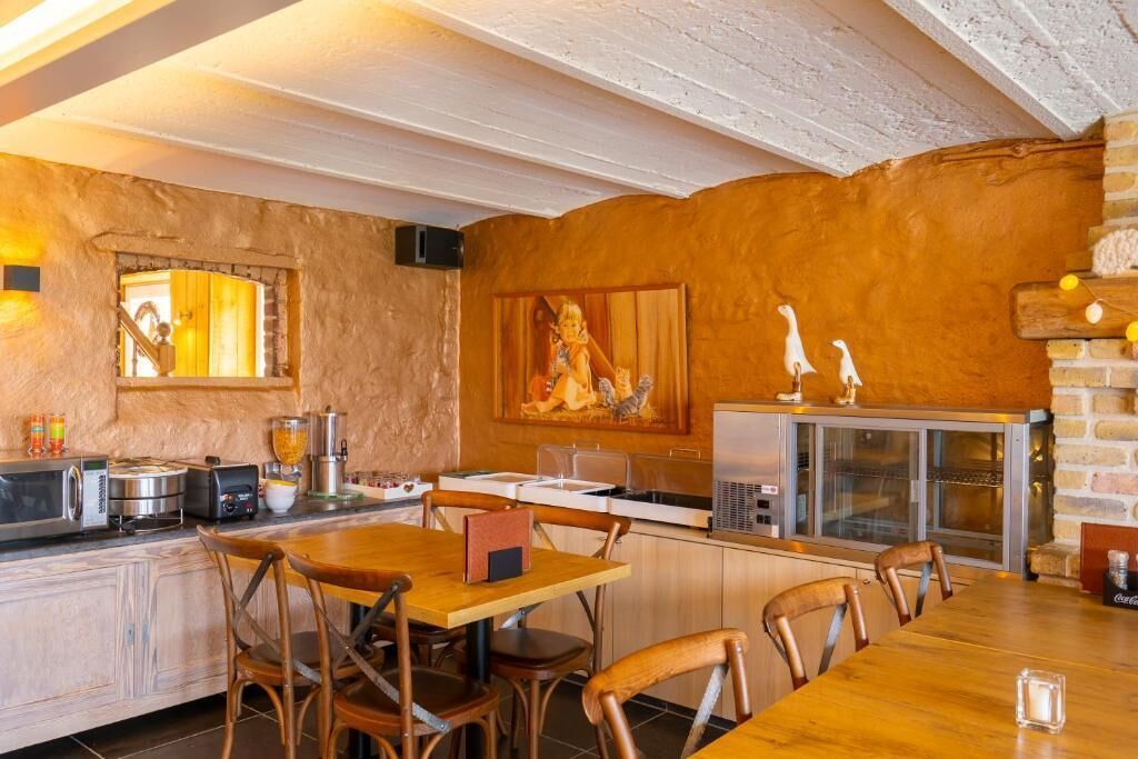 A rustic kitchen with wooden cabinets, a dining table, and chairs.