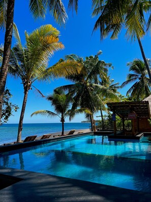A poolside area with a view of the ocean, palm trees, and a small structure labeled "Pool Bar". - Rinjani Beach Eco Resort (Tanjung)