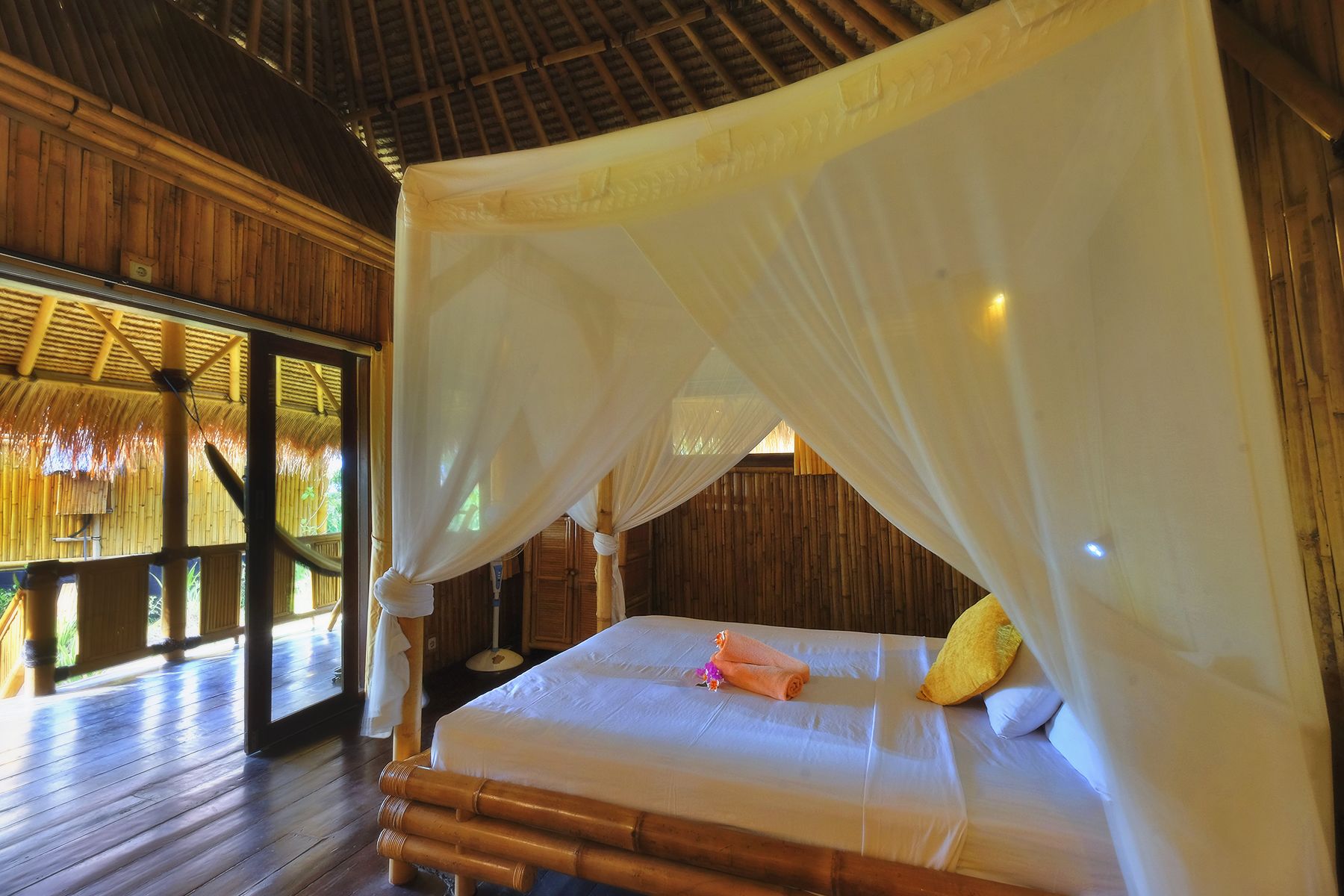 A room with a bed under a canopy, wooden walls, and a view of the outdoors.