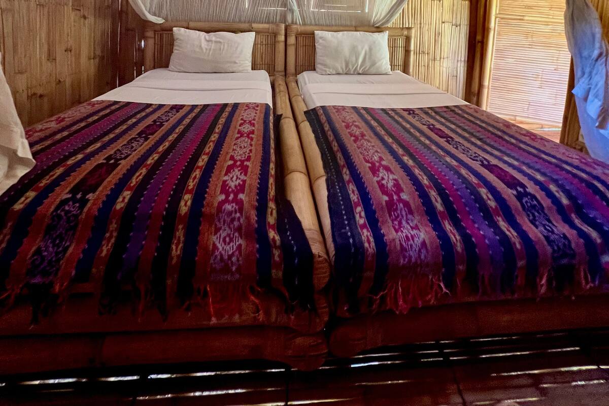 Ein Doppelbett mit gemustertem Bettbezug, einem Holzkopfstück und weißen Kissen.