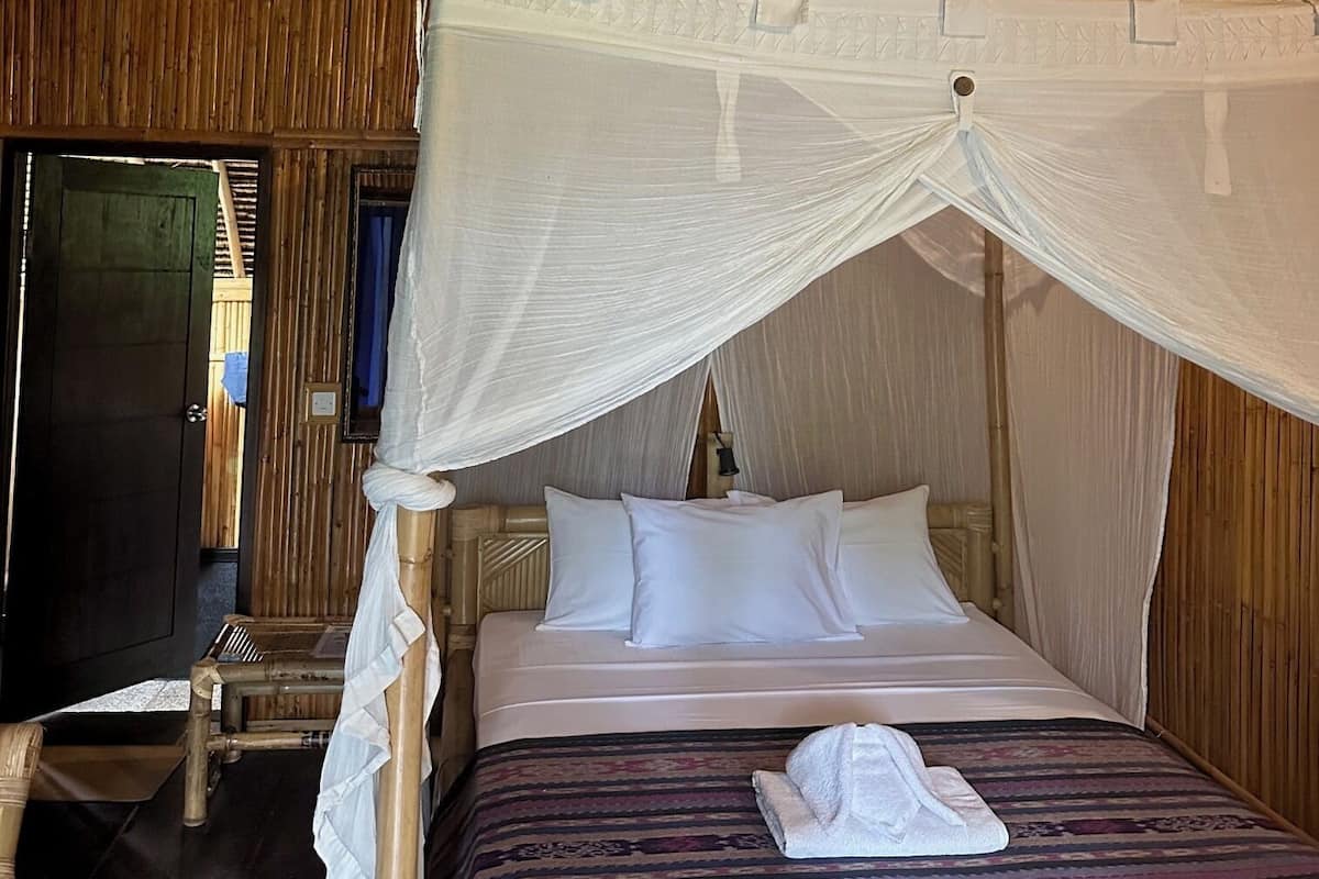 Ein Zimmer mit einem Bett unter einem Baldachin, Holzwänden und einer runden Hängeleuchte.