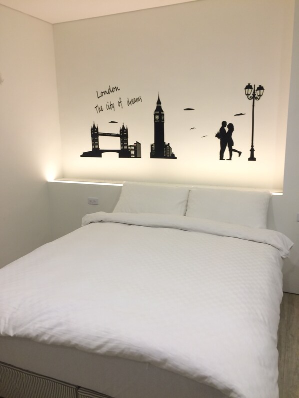 A hotel room with a large bed, white bedding, and a wall mural depicting London landmarks and a couple. - Taimali Hotel (Taimali)