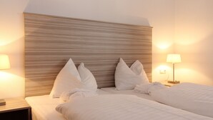 Habitación de hotel con una cama grande, dos mesitas de noche y un cabecero con líneas horizontales.