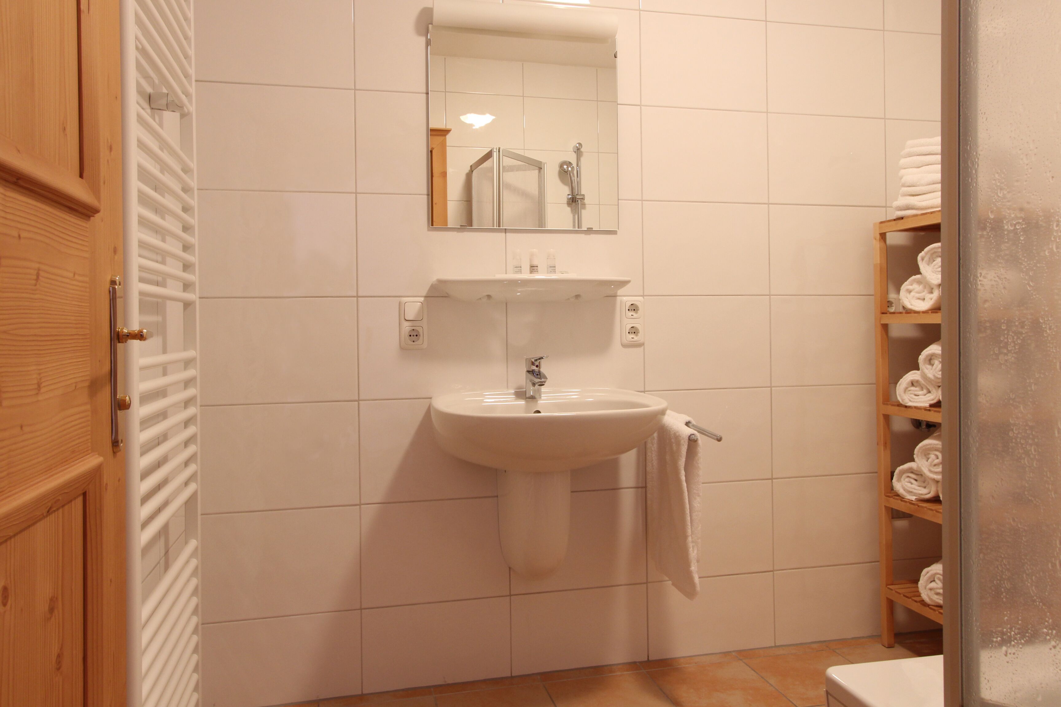 Un baño con lavabo blanco, espejo y barra para toallas.