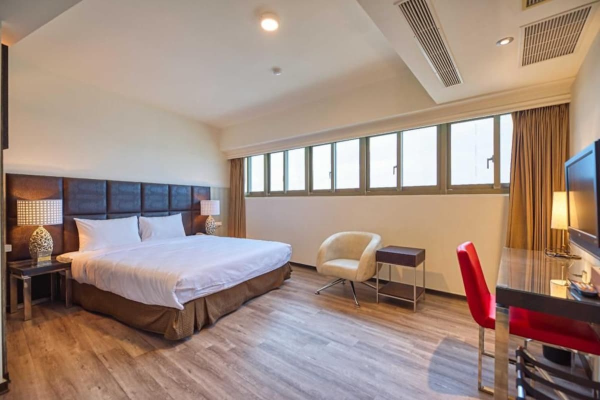 Une chambre d’hôtel avec un grand lit, un bureau, une chaise et un téléviseur.