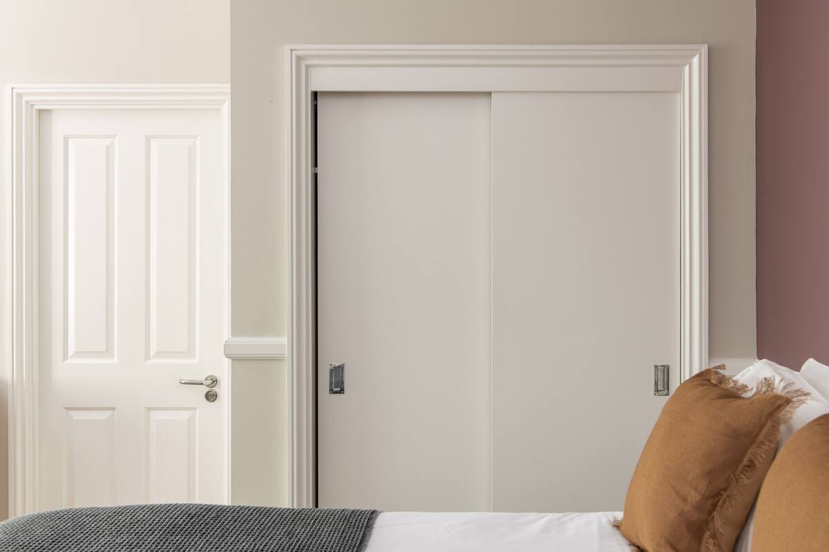 A bedroom with a bed, two doors, and a wall with a textured finish.