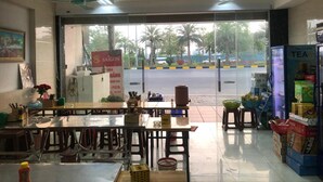 A restaurant with a glass door entrance, tables, chairs, ceiling fans, and a refrigerator stocked with beverages.