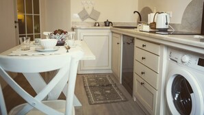 A compact kitchen with a washing machine, a coffee maker, and a small dining table with chairs. - Casa Camilla City (Padova)