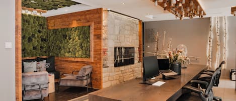 A modern reception area with a stone wall, green wall, and a fireplace. There are sofas and chairs for guests.