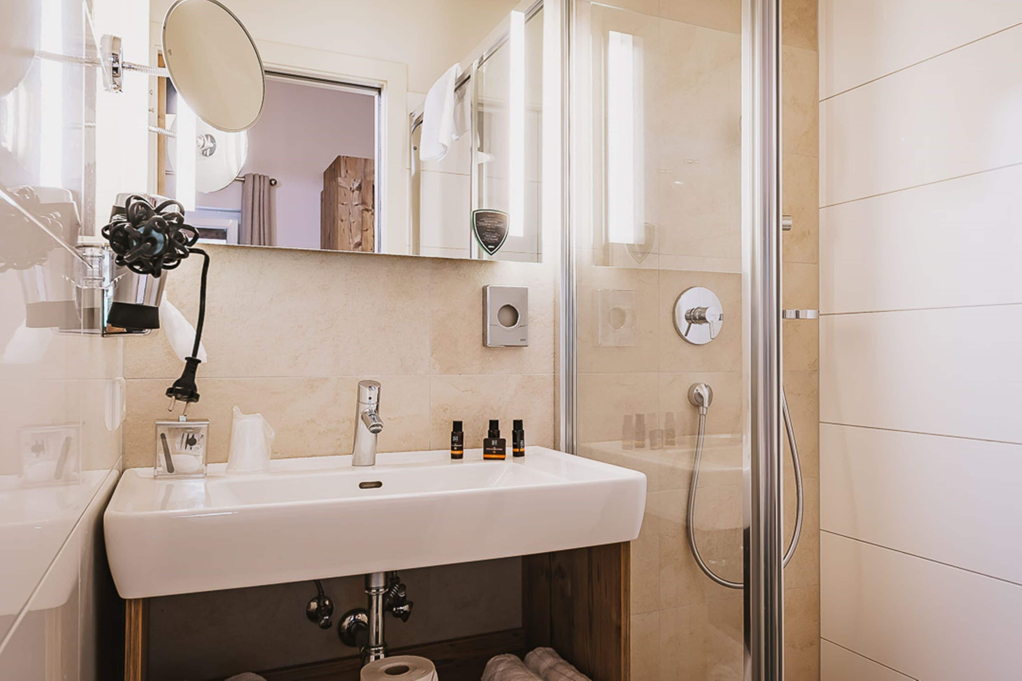 Un baño moderno con lavamanos, espejo y ducha blancos.