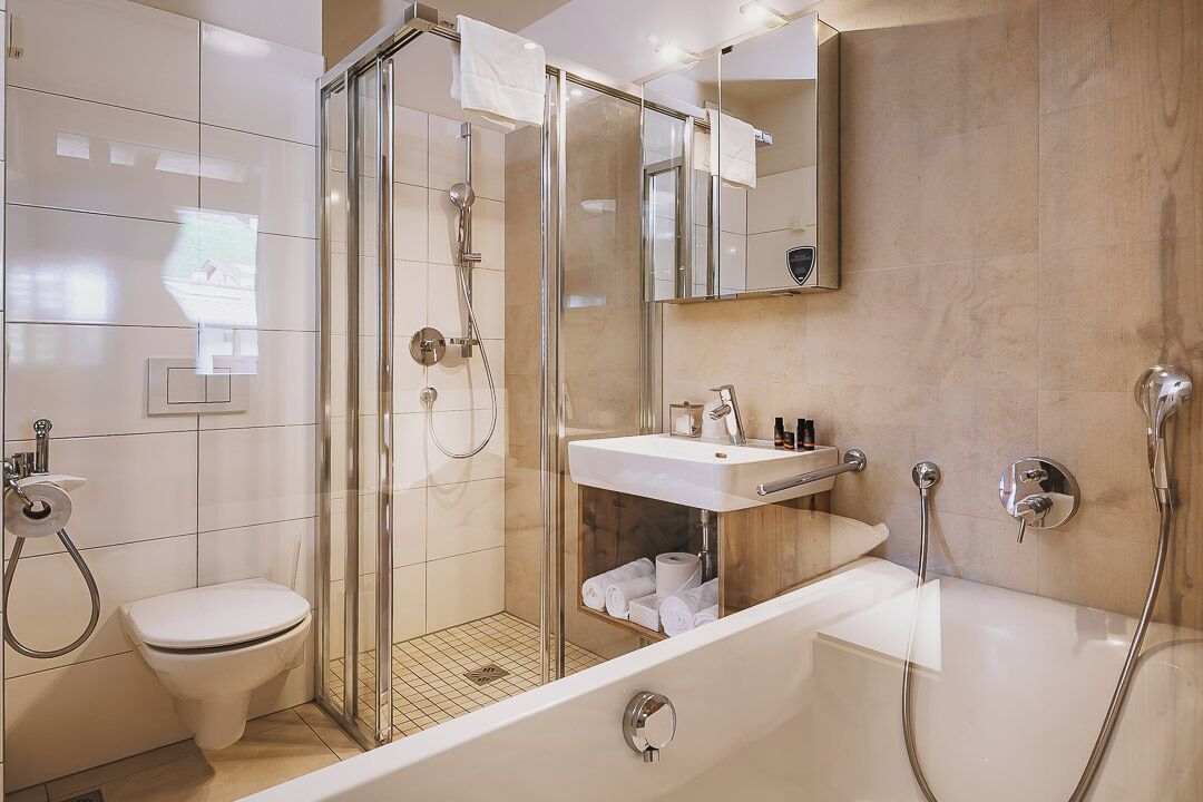 Une salle de bain moderne avec une douche à parois de verre, des toilettes, un lavabo avec un miroir et une baignoire.