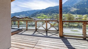 Une terrasse en bois offrant une vue sur une vallée et des montagnes.