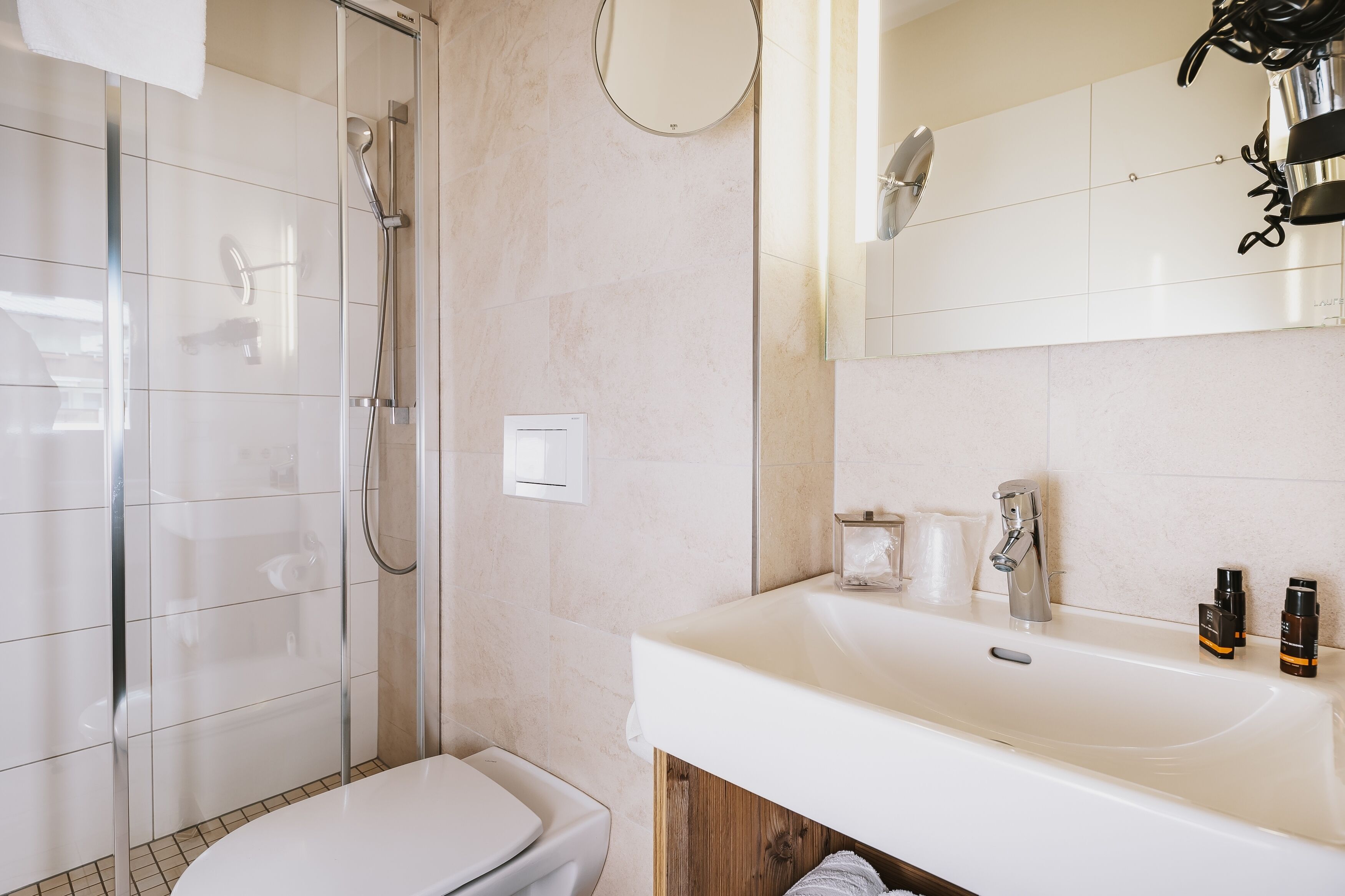 Une salle de bain moderne avec une douche à parois de verre, des toilettes blanches et un lavabo équipé de produits de toilette.