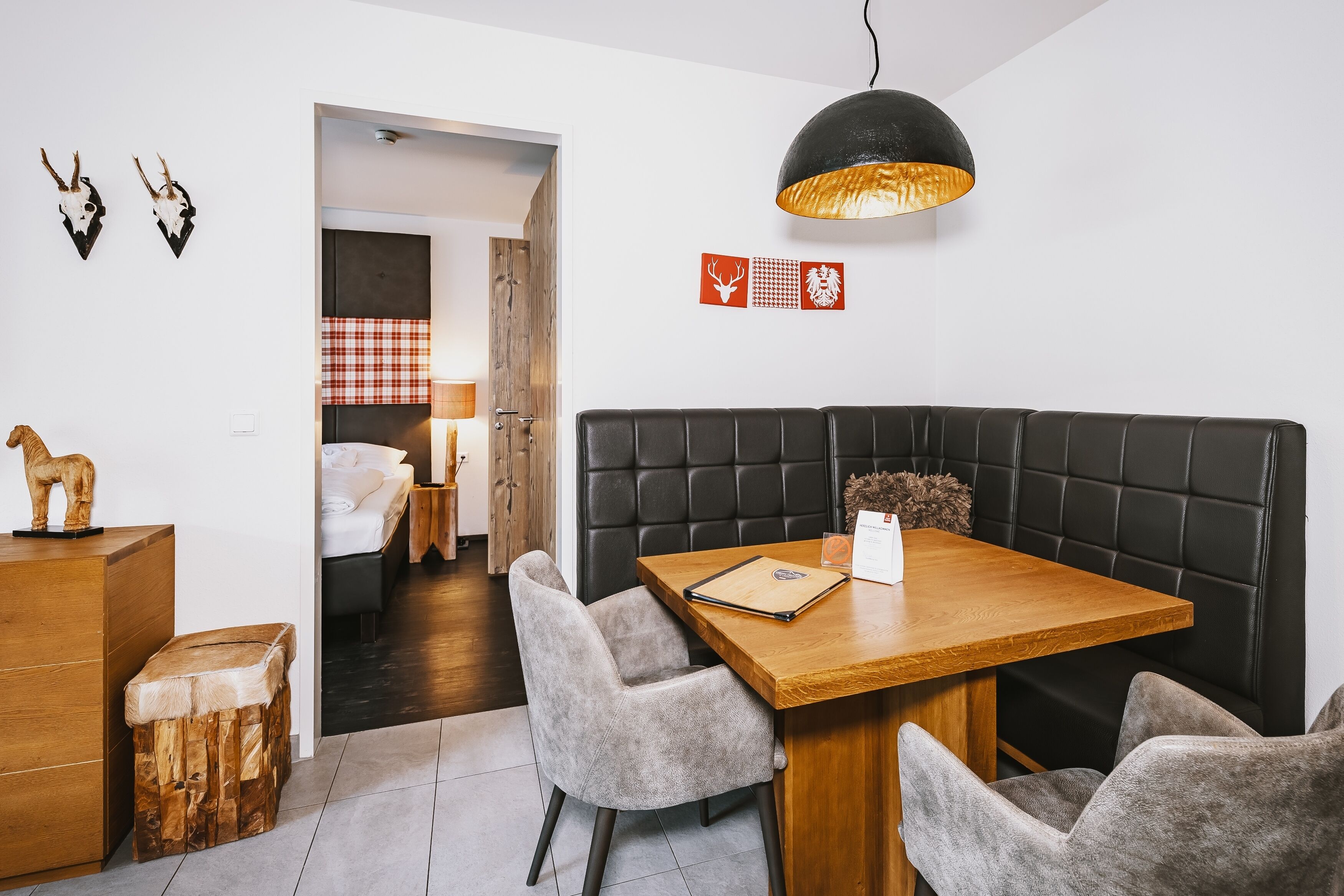 A modern dining area with a wooden table, grey upholstered chairs, and a black cushioned bench.