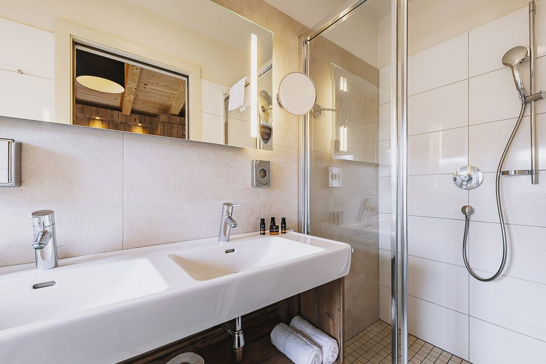 A modern bathroom with a large sink, mirror, and shower.