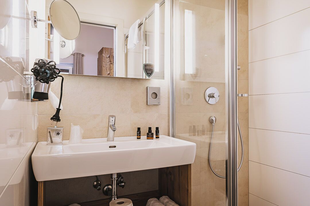 Un baño moderno con lavamanos, espejo y ducha blancos.