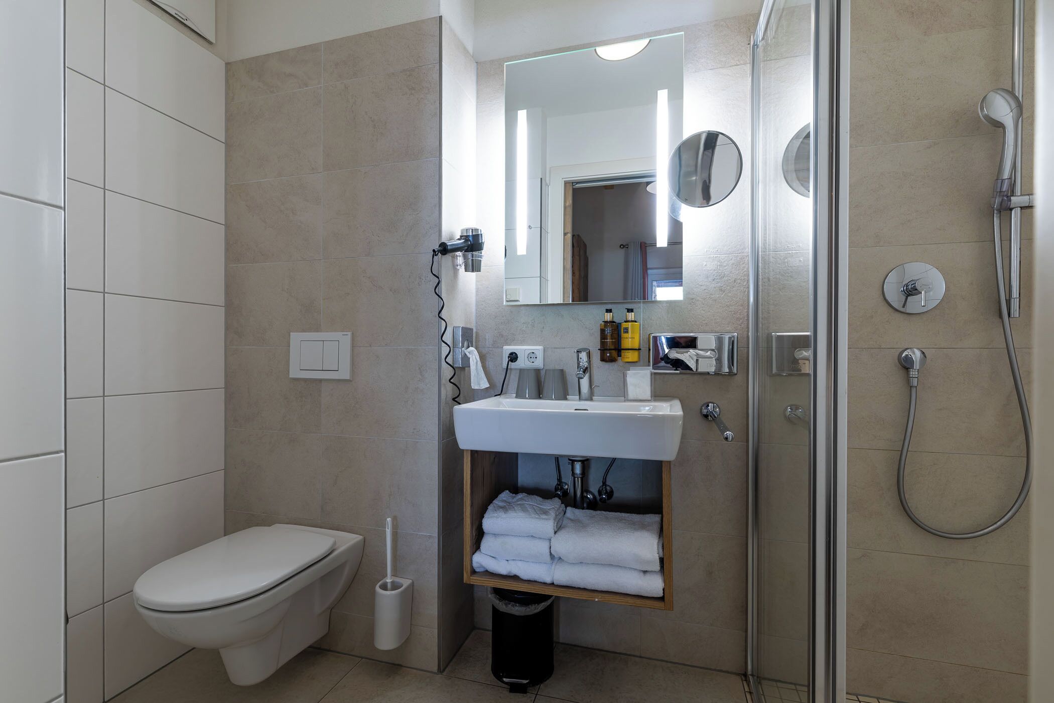A modern bathroom with a toilet, sink, and shower.