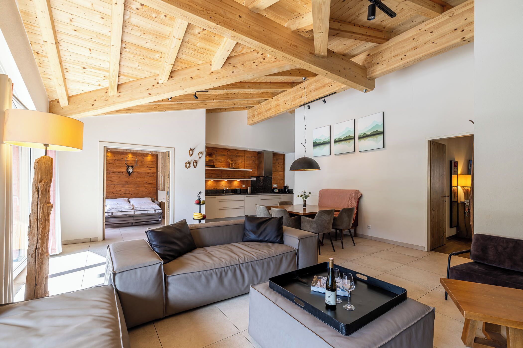 A modern living room with a wooden ceiling, a sofa, a coffee table, and a kitchen in the background.