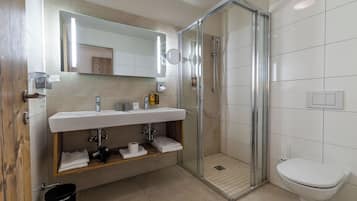 Une salle de bain moderne avec une douche à parois de verre, un lavabo blanc et des toilettes.